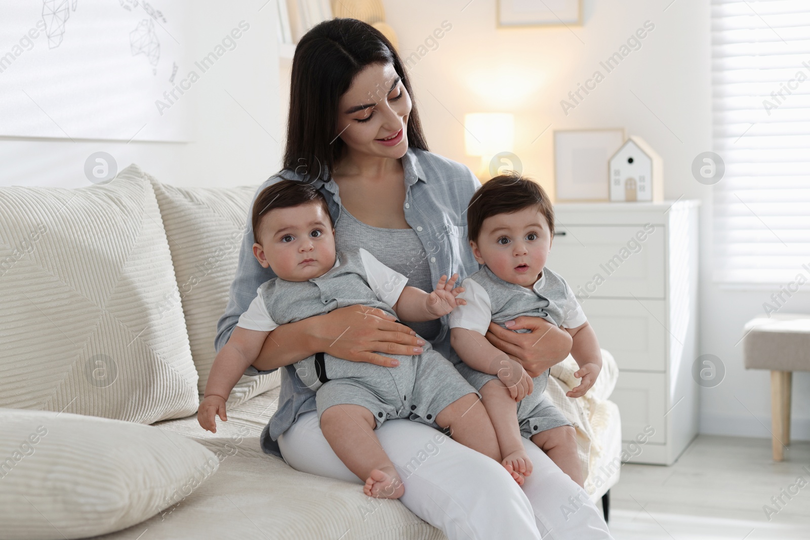 Mother with her cute twin babies on sofa at home Photo of Mother with her cute twin babies on sofa at home