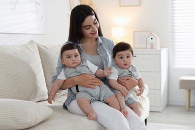 Photo of Mother with her cute twin babies on sofa at home