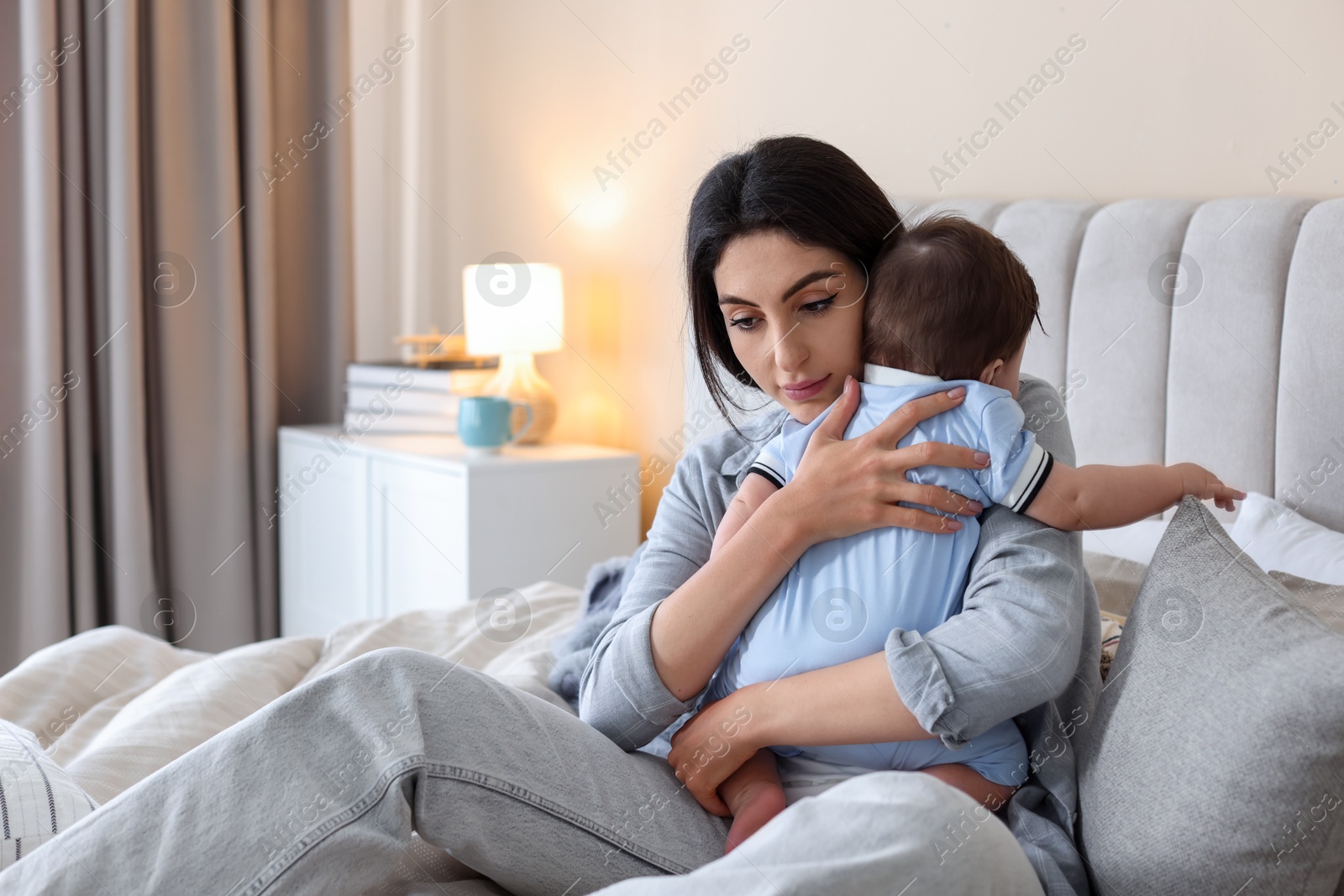 Woman suffering from postpartum depression with her little baby on bed at home. Space for text Photo of Woman suffering from postpartum depression with her little baby on bed at home. Space for text