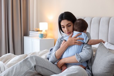 Photo of Woman suffering from postpartum depression with her little baby on bed at home. Space for text