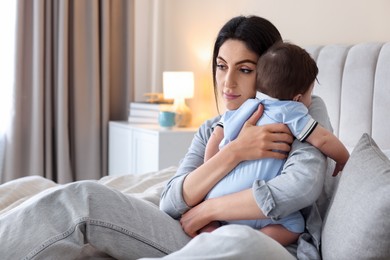 Photo of Woman suffering from postpartum depression with her little baby on bed at home. Space for text