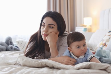 Photo of Woman suffering from postpartum depression with her little baby on bed at home