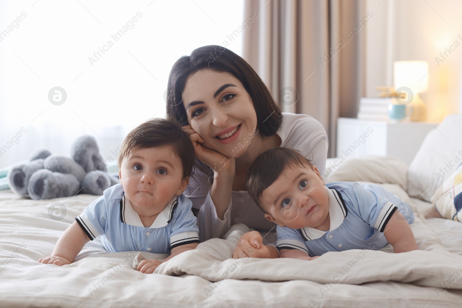 Mother with her cute twin babies on bed at home Photo of Mother with her cute twin babies on bed at home