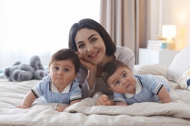 Photo of Mother with her cute twin babies on bed at home