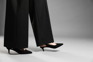 Photo of Businesswoman in high heeled shoes on gray background, closeup. Space for text