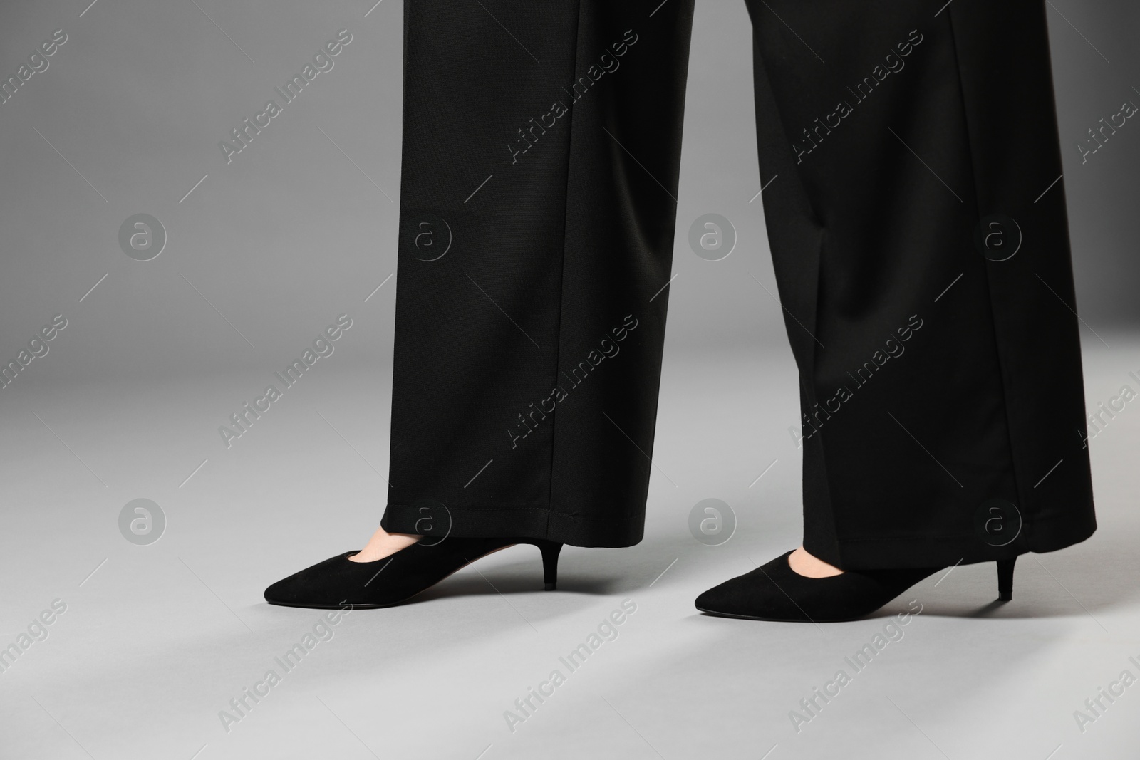 Businesswoman in high heeled shoes on gray background, closeup Photo of Businesswoman in high heeled shoes on gray background, closeup