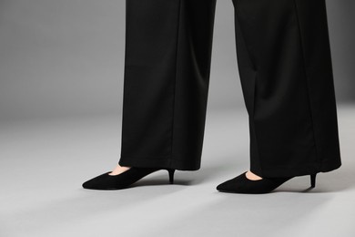 Photo of Businesswoman in high heeled shoes on gray background, closeup