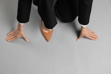 Photo of Businesswoman in starting position on gray background, top view. Space for text