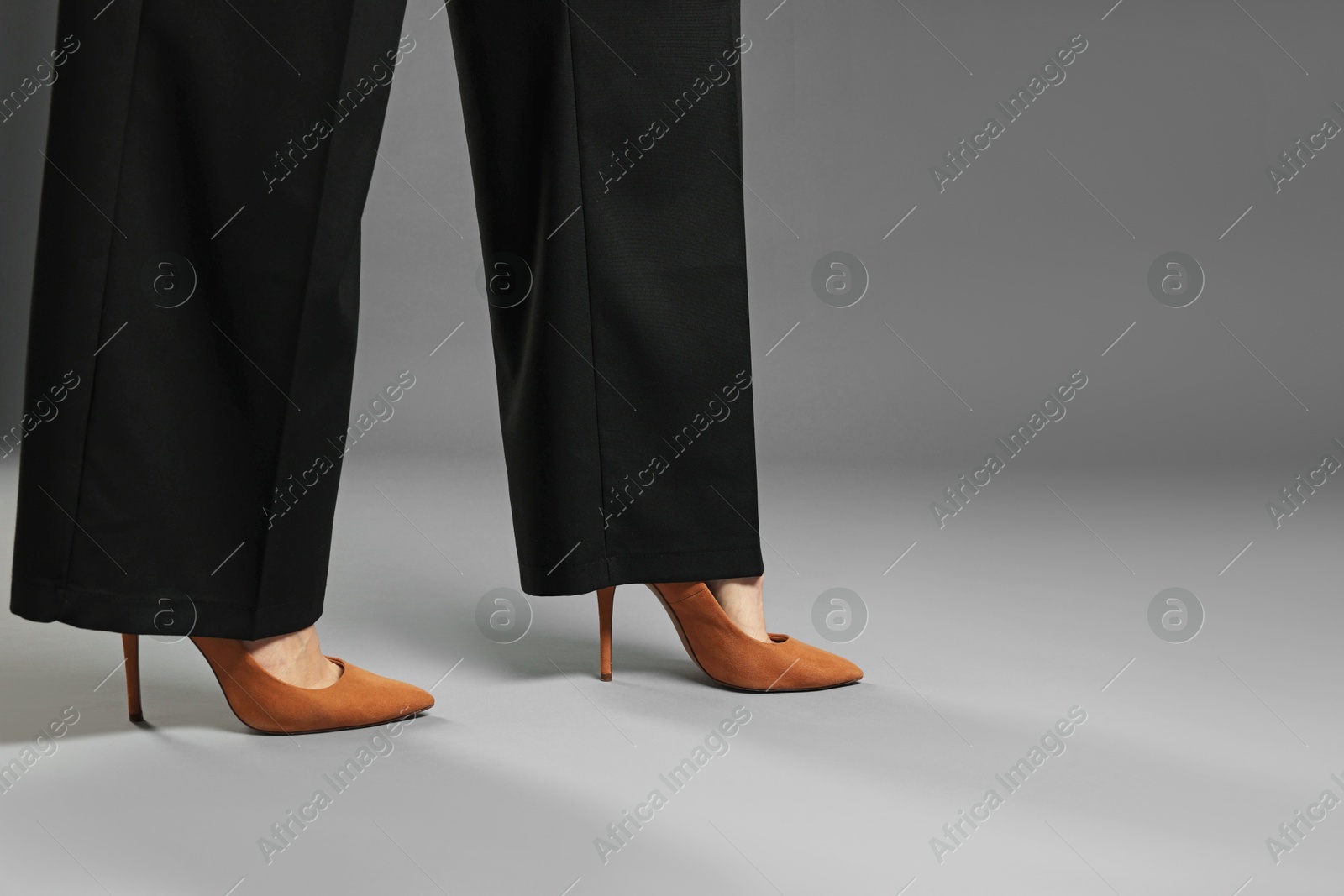Businesswoman in high heeled shoes on gray background, closeup. Space for text Photo of Businesswoman in high heeled shoes on gray background, closeup. Space for text
