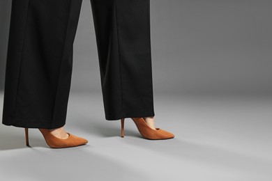 Photo of Businesswoman in high heeled shoes on gray background, closeup. Space for text