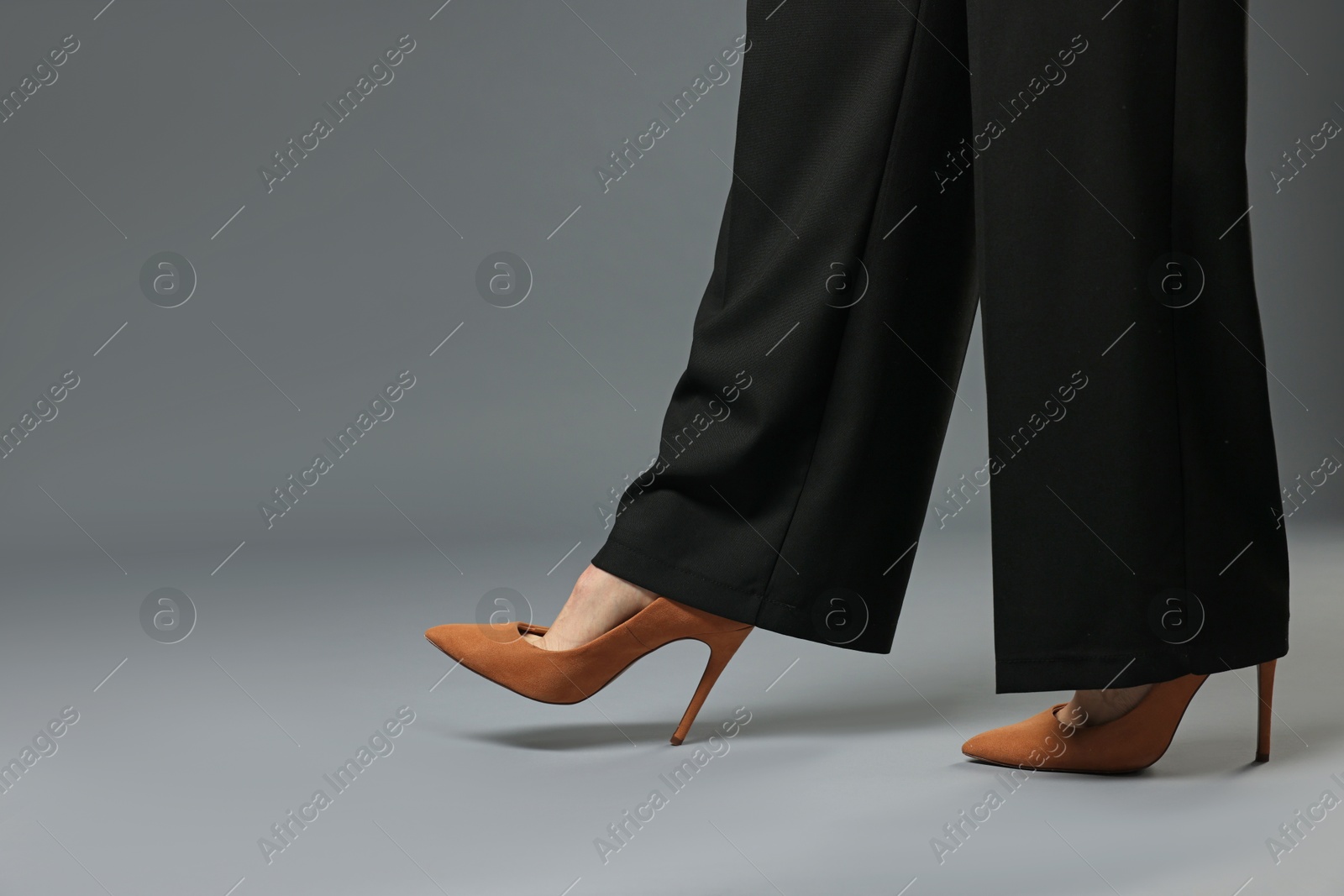 Businesswoman in high heeled shoes on gray background, closeup. Space for text Photo of Businesswoman in high heeled shoes on gray background, closeup. Space for text