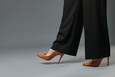 Photo of Businesswoman in high heeled shoes on gray background, closeup. Space for text