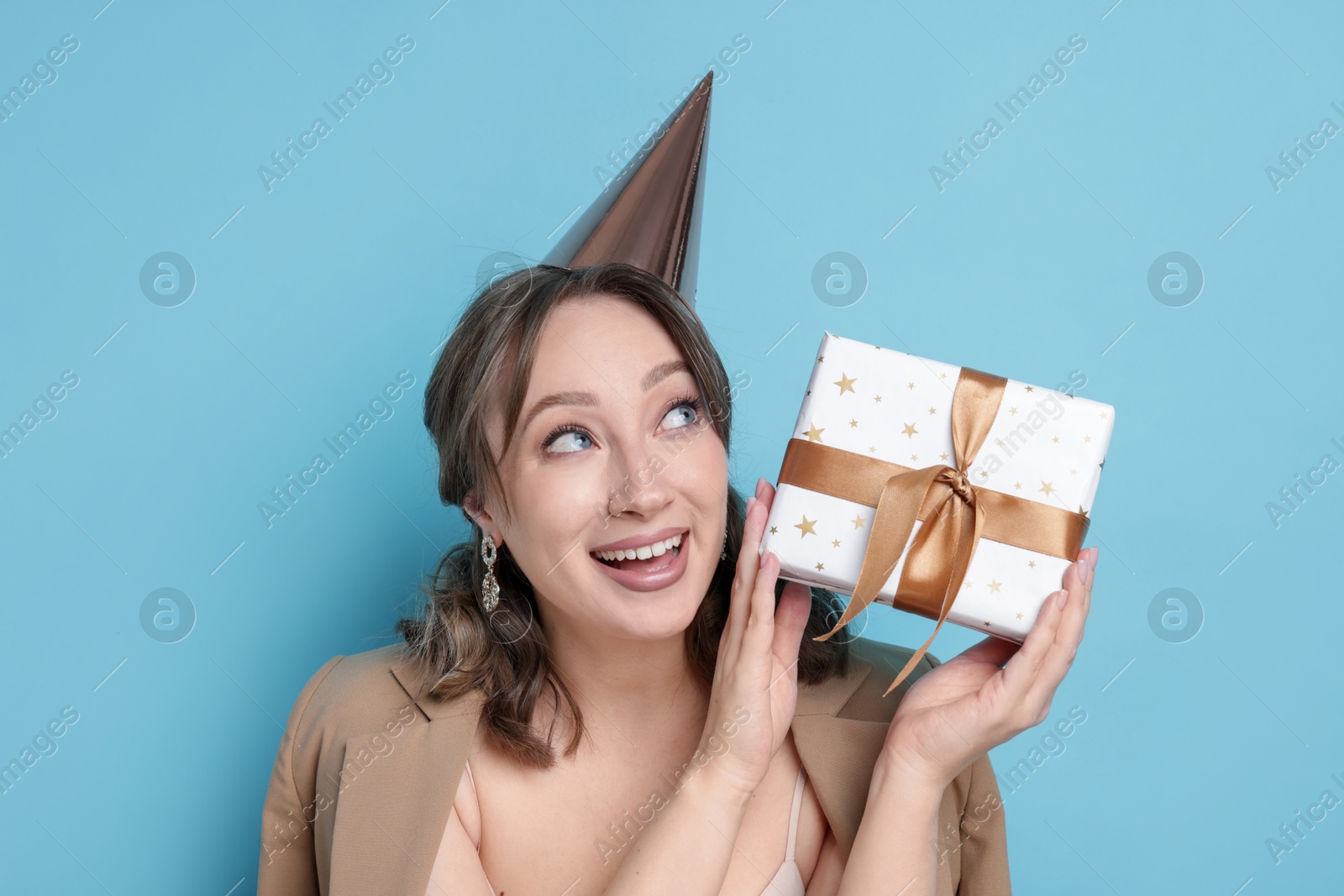 Birthday celebration. Woman with gift on light blue background Photo of Birthday celebration. Woman with gift on light blue background