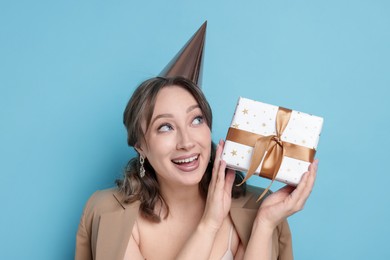 Photo of Birthday celebration. Woman with gift on light blue background