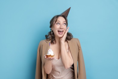 Photo of Birthday celebration. Woman with cupcake on light blue background