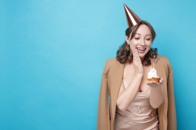 Photo of Birthday celebration. Woman with cupcake on light blue background. Space for text