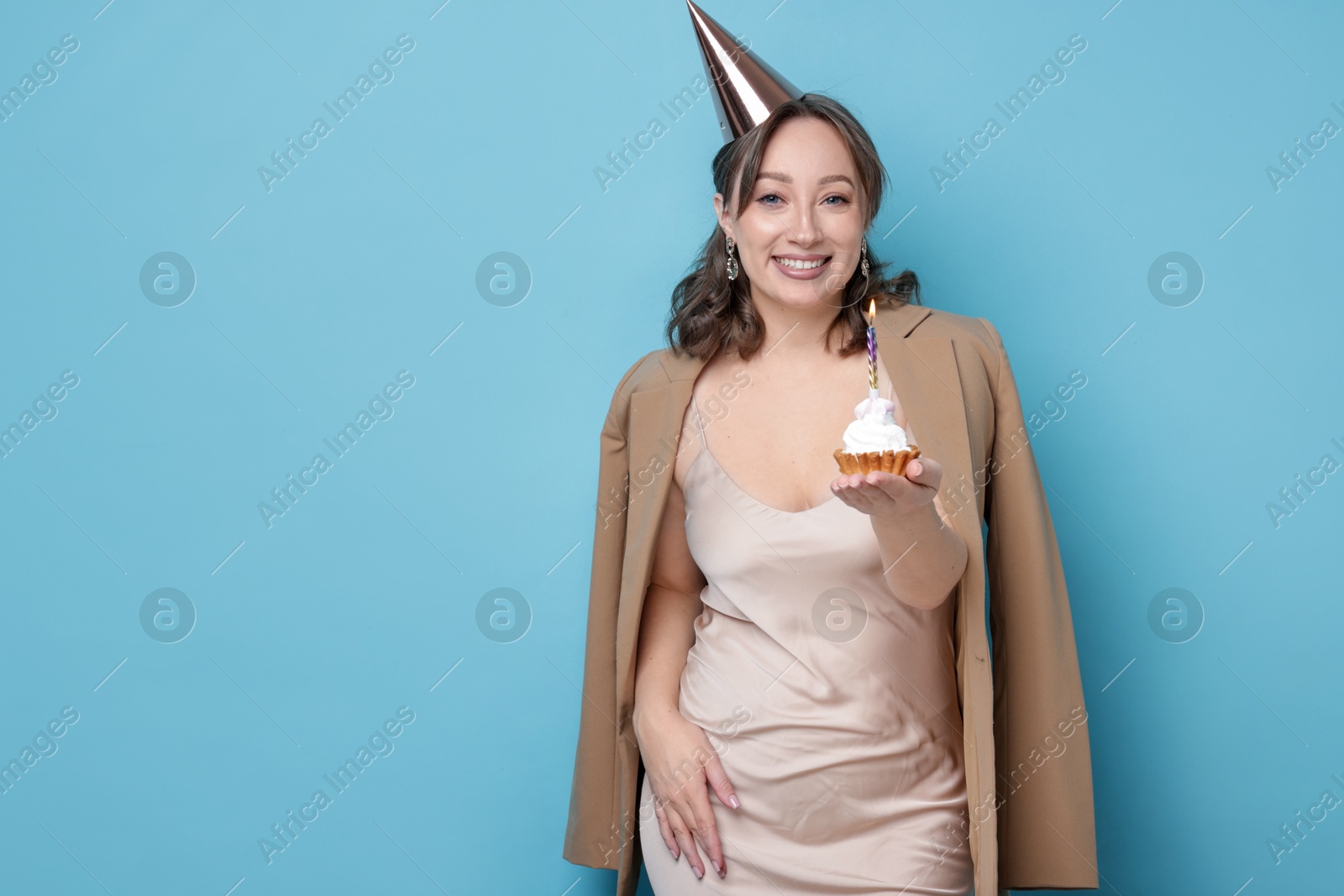 Birthday celebration. Woman with cupcake on light blue background. Space for text Photo of Birthday celebration. Woman with cupcake on light blue background. Space for text