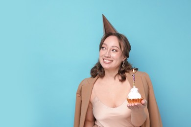 Photo of Birthday celebration. Woman with cupcake on light blue background. Space for text