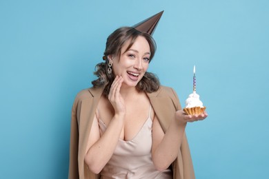 Photo of Birthday celebration. Woman with cupcake on light blue background