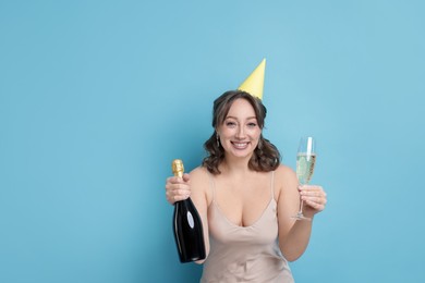 Photo of Birthday celebration. Woman with sparkling wine on light blue background. Space for text
