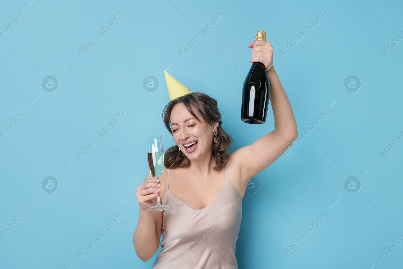 Birthday celebration. Woman with sparkling wine on light blue background Photo of Birthday celebration. Woman with sparkling wine on light blue background