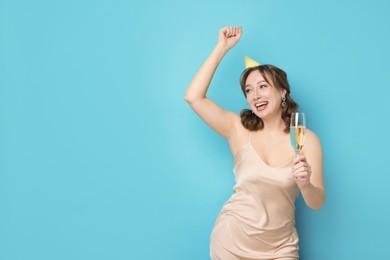 Photo of Birthday celebration. Woman with glass of sparkling wine on light blue background. Space for text