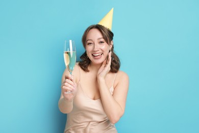 Photo of Birthday celebration. Woman with glass of sparkling wine on light blue background
