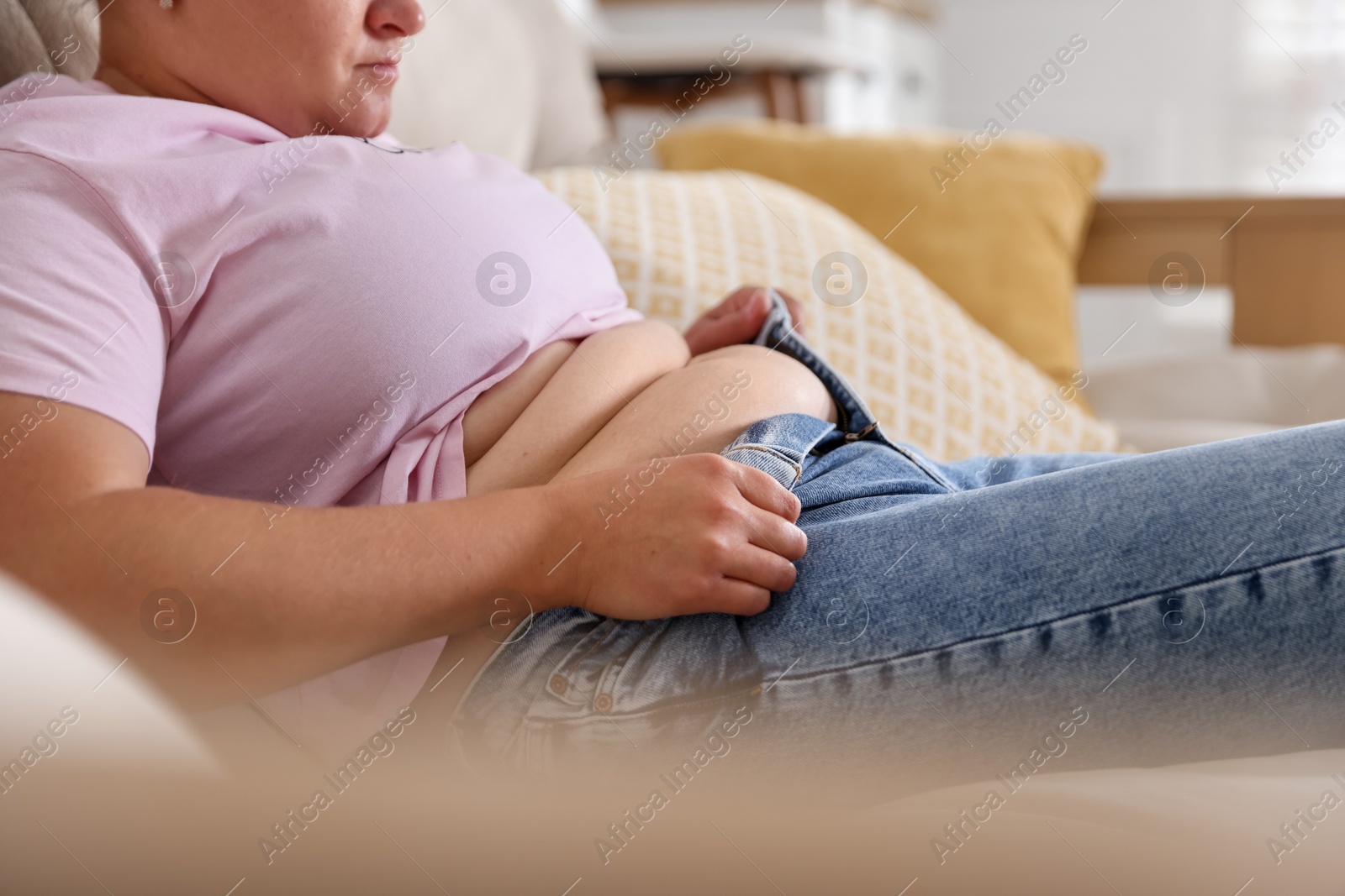 Overweight woman trying to put on tight jeans at home, closeup Photo of Overweight woman trying to put on tight jeans at home, closeup