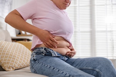 Photo of Woman with excessive belly fat at home, closeup. Overweight problem