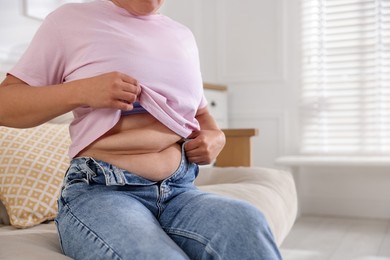 Photo of Woman with excessive belly fat at home, closeup. Overweight problem