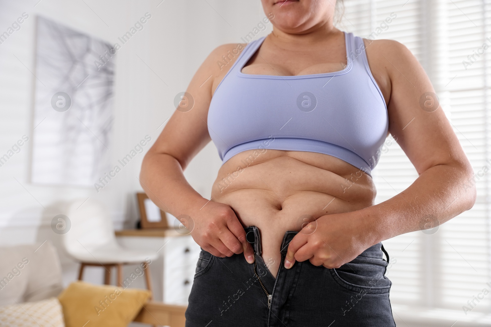 Overweight woman trying to put on tight jeans at home, closeup Photo of Overweight woman trying to put on tight jeans at home, closeup