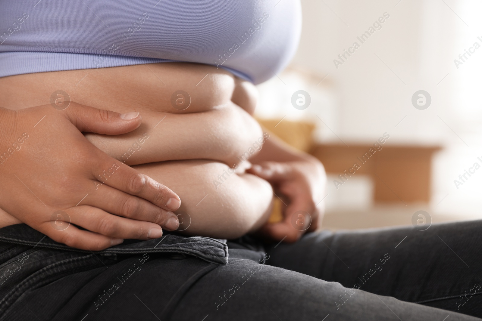 Woman with excessive belly fat at home, closeup. Overweight problem Photo of Woman with excessive belly fat at home, closeup. Overweight problem