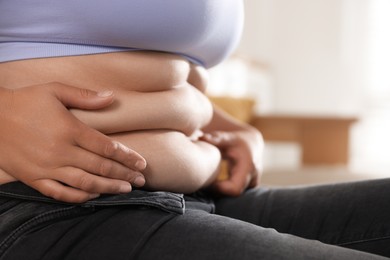 Photo of Woman with excessive belly fat at home, closeup. Overweight problem