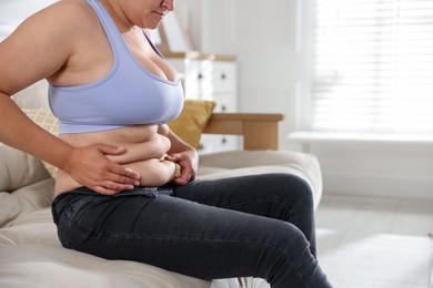 Photo of Woman with excessive belly fat at home, closeup and space for text. Overweight problem