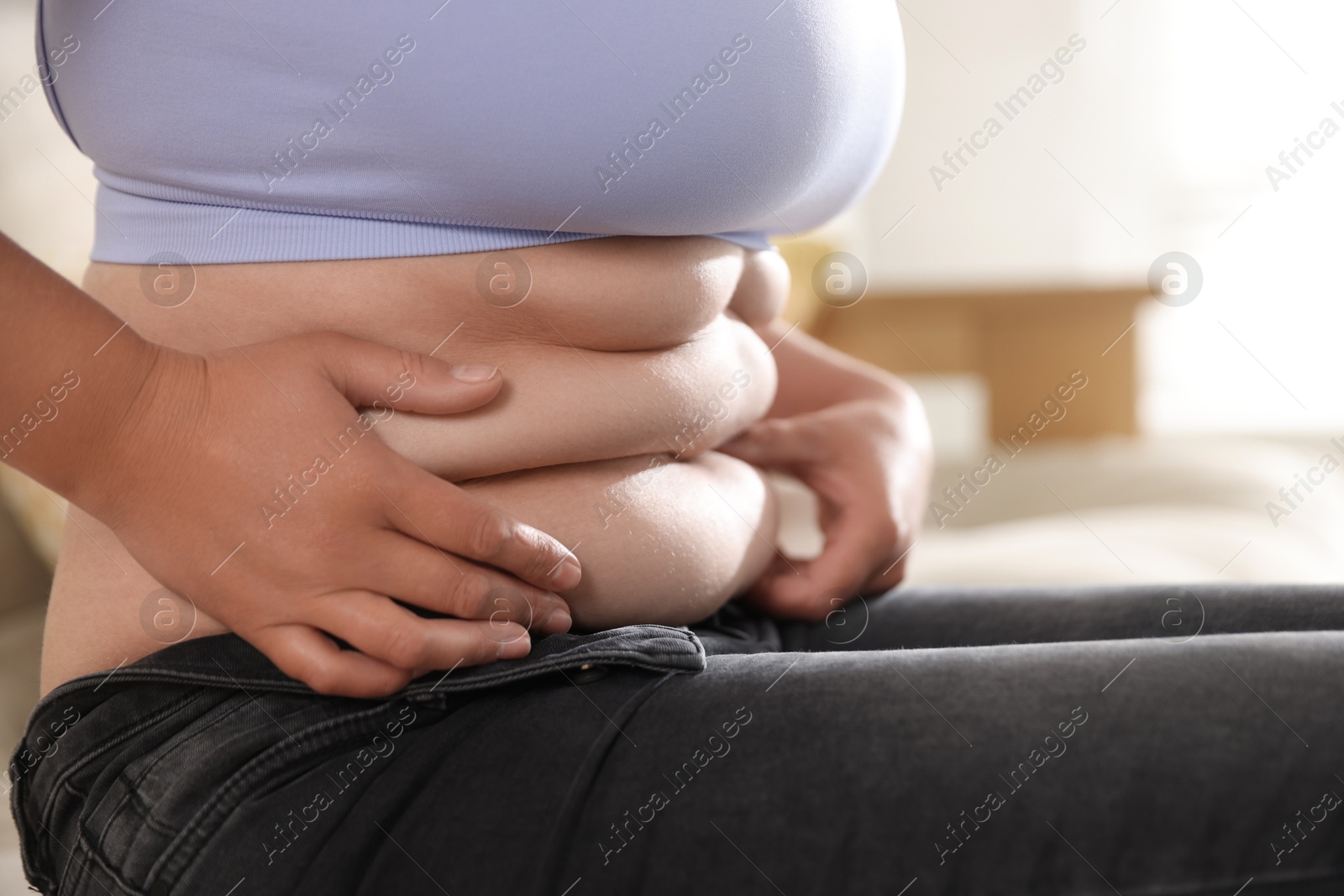 Woman with excessive belly fat at home, closeup. Overweight problem Photo of Woman with excessive belly fat at home, closeup. Overweight problem