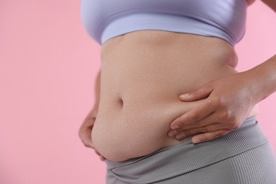 Photo of Woman with excessive belly fat on pink background, closeup. Overweight problem