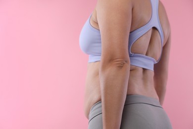 Photo of Woman with excessive belly fat on pink background, closeup and space for text. Overweight problem