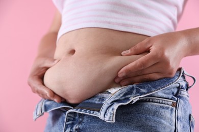 Photo of Woman with excessive belly fat on pink background, closeup. Overweight problem