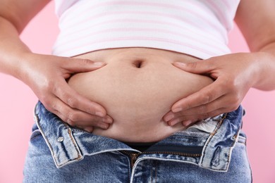 Photo of Woman with excessive belly fat on pink background, closeup. Overweight problem