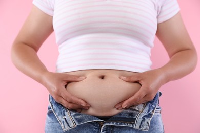 Photo of Woman with excessive belly fat on pink background, closeup. Overweight problem