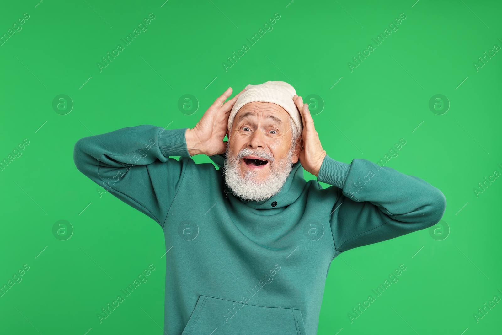 Elderly man in stylish outfit on green background Photo of Elderly man in stylish outfit on green background