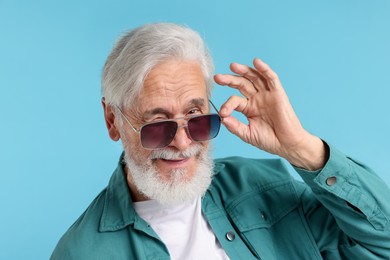Photo of Elderly man in stylish sunglasses on light blue background