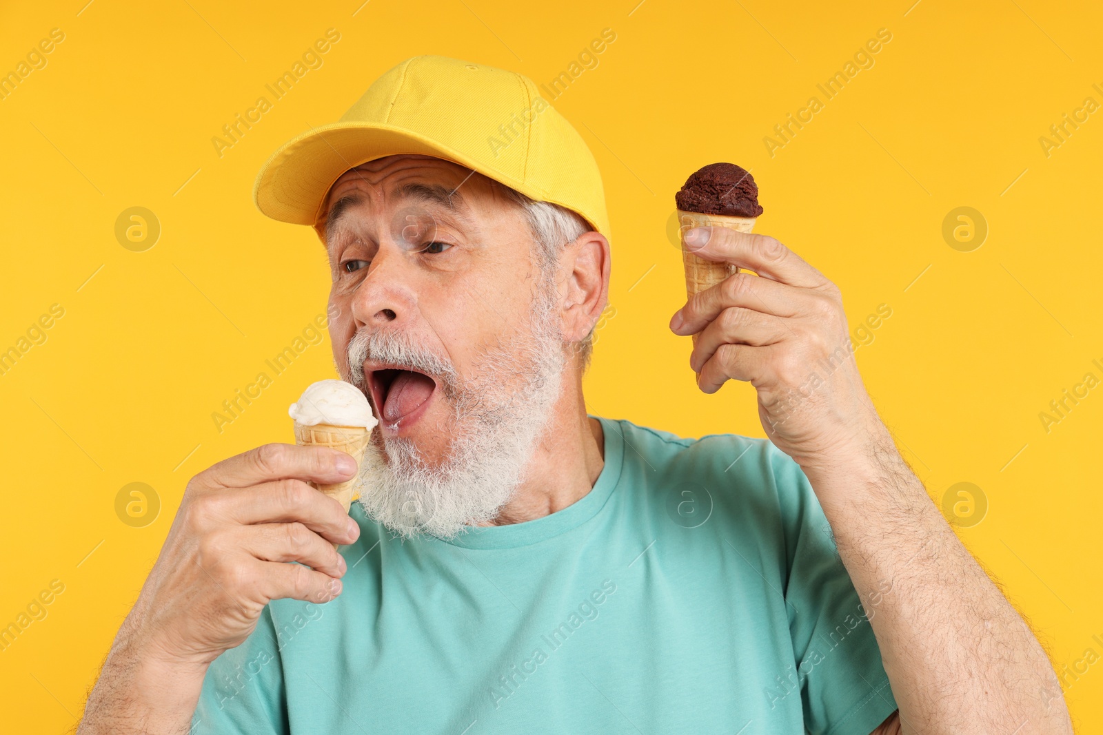 Elderly man in stylish outfit eating ice cream on orange background Photo of Elderly man in stylish outfit eating ice cream on orange background