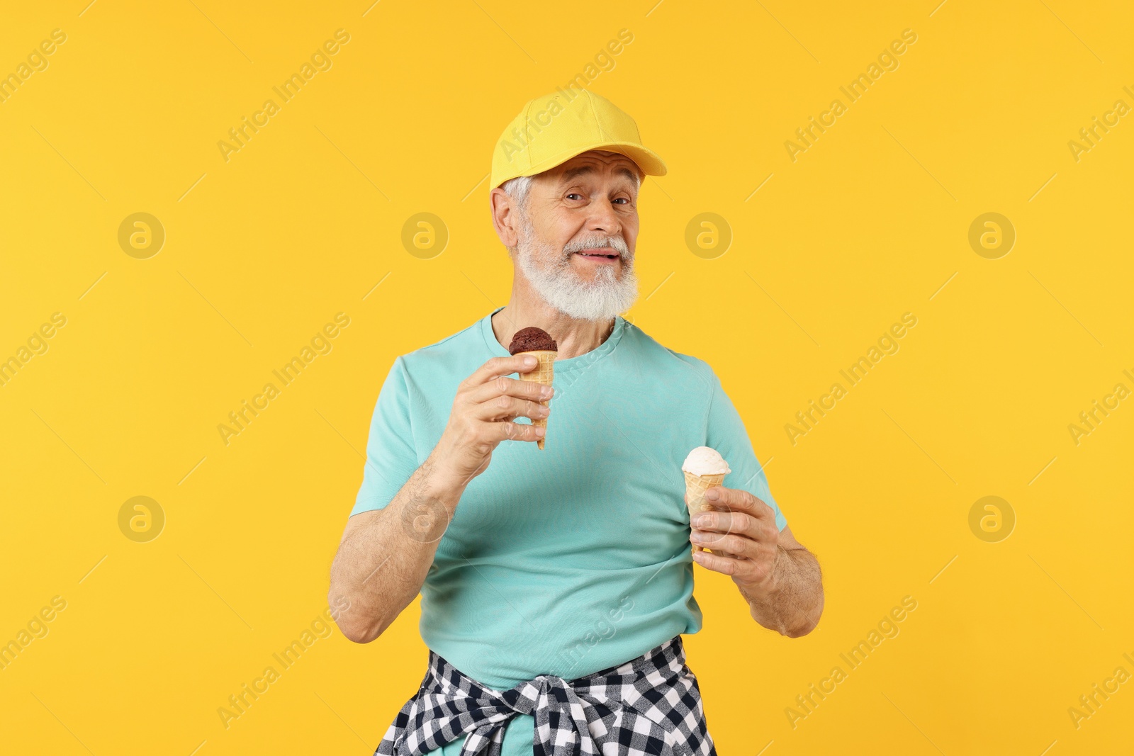 Elderly man in stylish outfit holding ice cream on orange background Photo of Elderly man in stylish outfit holding ice cream on orange background