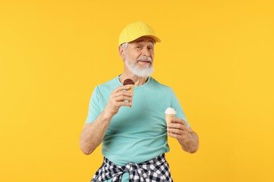 Photo of Elderly man in stylish outfit holding ice cream on orange background