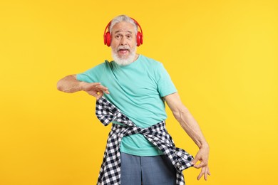 Photo of Elderly man in headphones on orange background