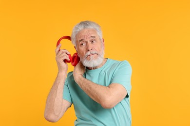 Photo of Elderly man with headphones on orange background