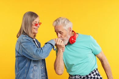 Photo of Senior couple in stylish outfits on orange background
