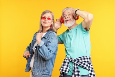 Photo of Senior couple in stylish outfits on orange background