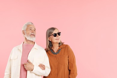 Photo of Senior couple in stylish outfits on pink background, space for text